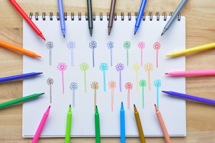 カラフルなペンで描かれた花のイラストと、周囲に並ぶ色とりどりのペン