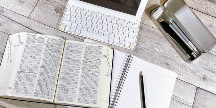 机の上に広げた参考書とノート、キーボードや筆記用具が並ぶ学習環境