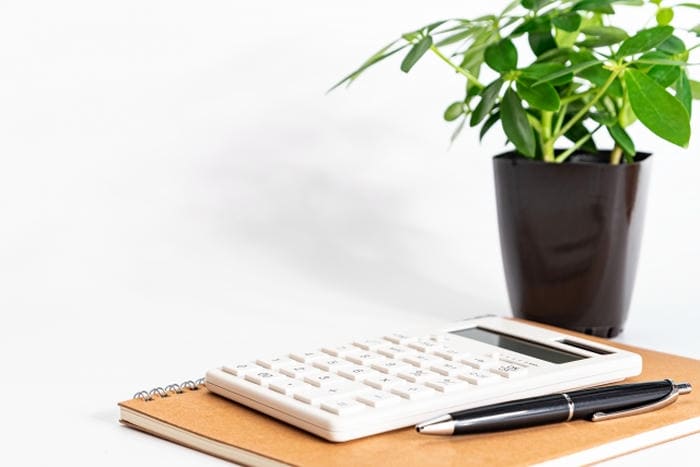 ノートの上に置かれた電卓とペン