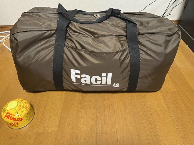 室内で撮影した小川テント(キャンパルジャパン)「ファシル」の収納バッグ。サイズ比較用にイワタニプリムスのガスカートリッジが手前に置かれている。
