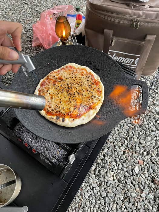 マルチグリドルのピザをバーナーで炙ってチーズに焼き色をつけている様子
