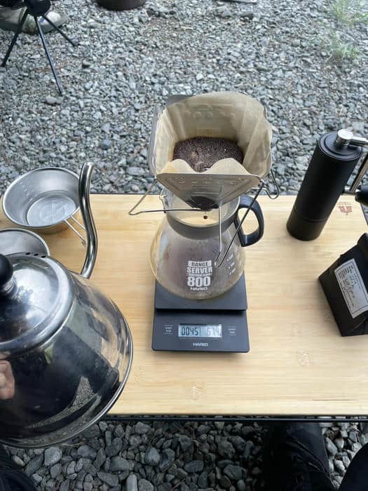 キャンプ場で挽いたコーヒー豆をドリッパーに入れてハンドドリップする様子
